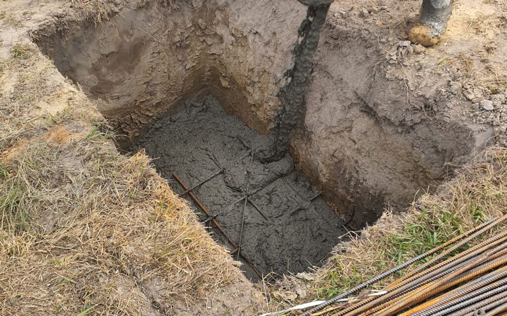 Builder filling a footing hole with concrete