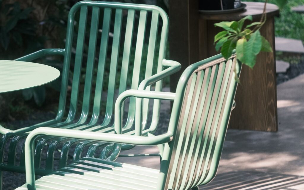Metal garden chairs and table in dappled shade