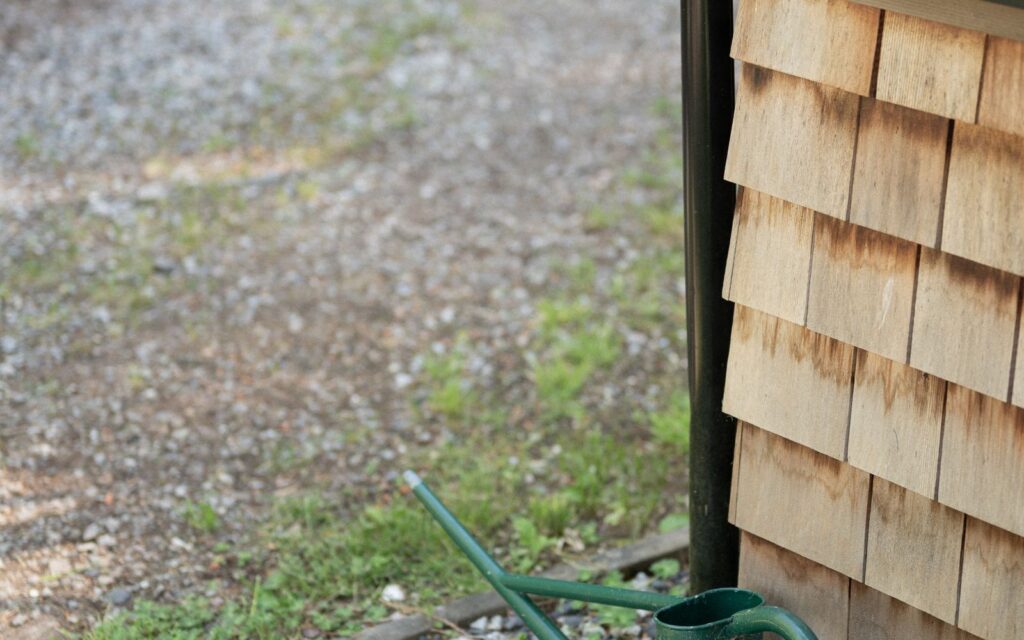 Watering can beside a wooden shed on a gravel path