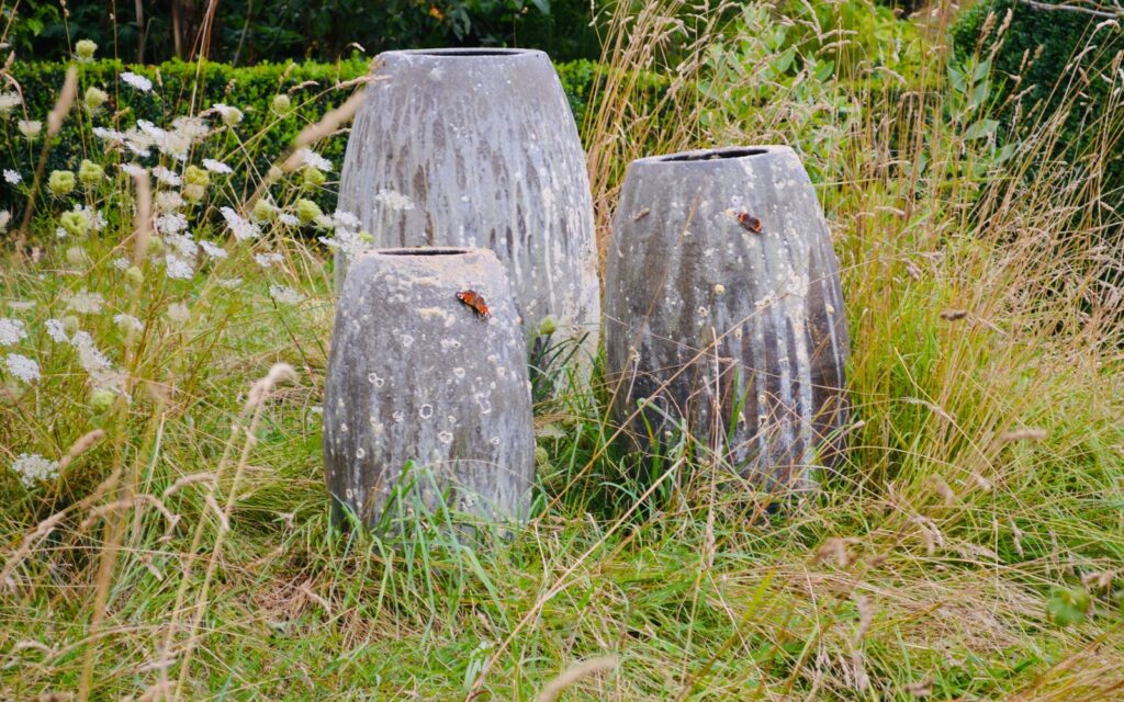 Three large stone planters in a garden