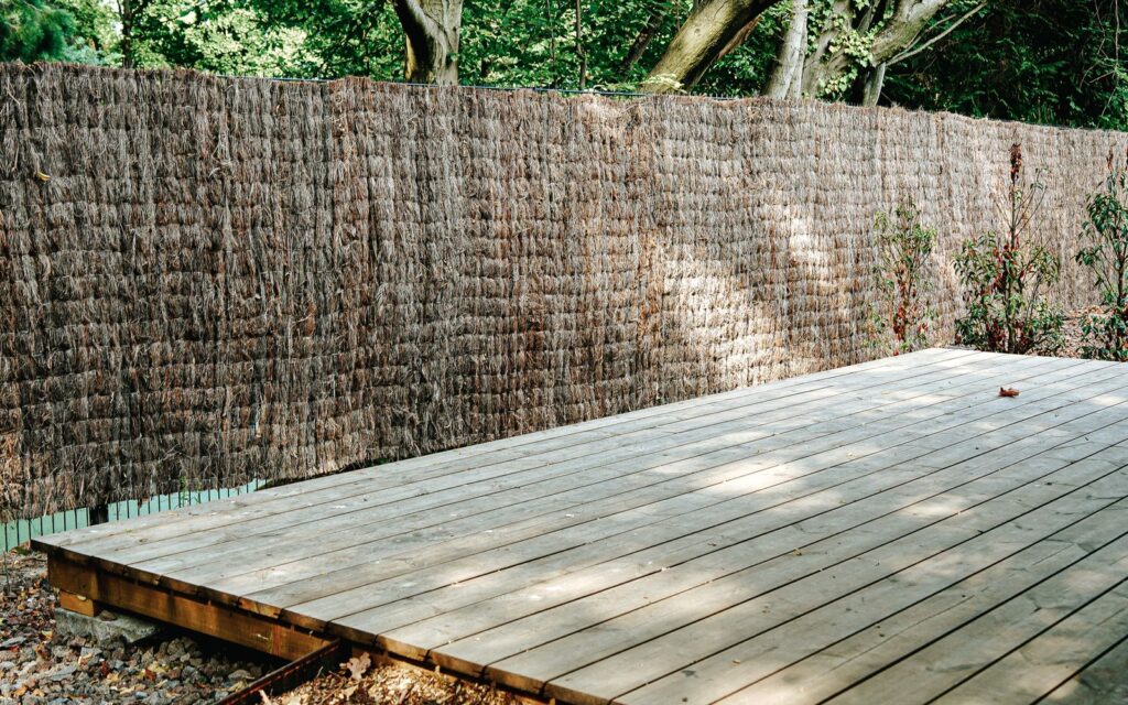 Wooden deck sheltered by a privacy fence and trees
