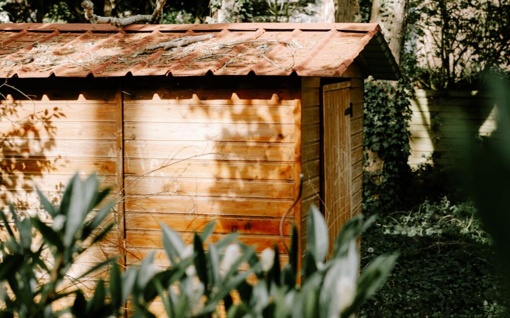 Wooden garden shed surrounded by greenery