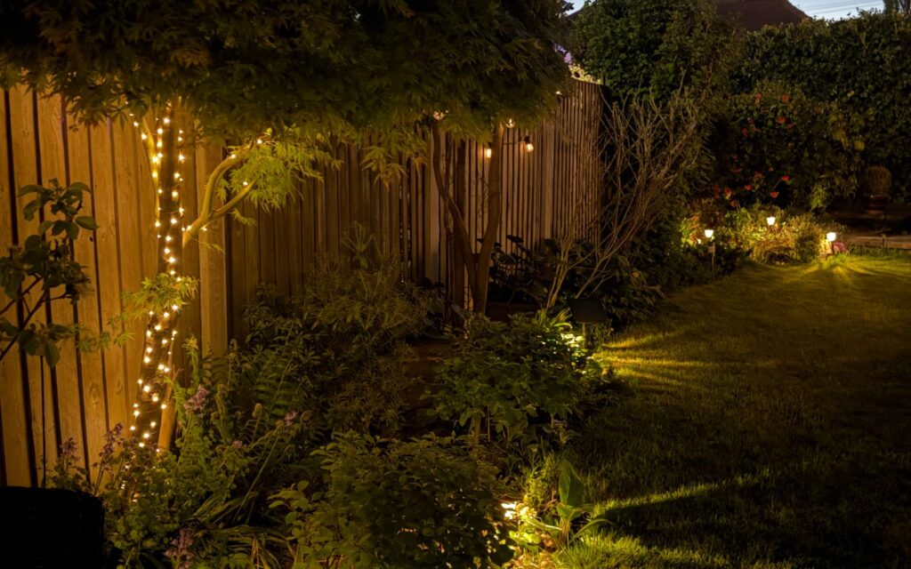 Small backyard garden lit with fairy lights at dusk