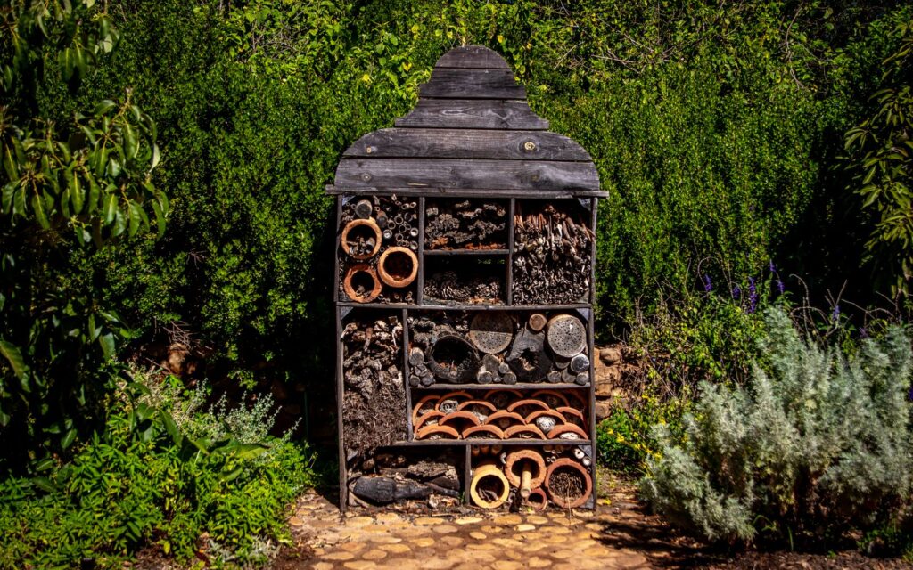 Wooden insect hotel among garden plants