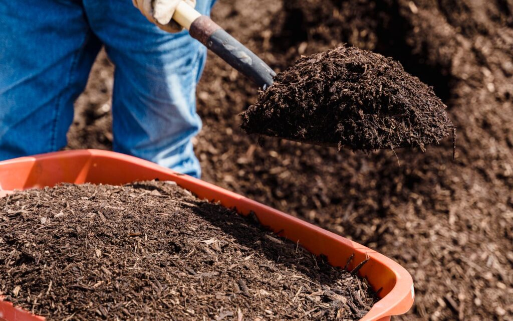 Shovelling homemade compost into a bin